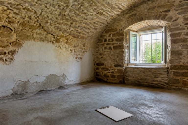 Sachlich beleuchteter Natursteinkeller mit dezent sichtbarer Feuchtespur und geöffnetem Fenster in einem älteren Pfälzer Wohnhaus
